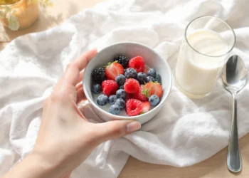 Healthy breakfast bowl with oatmeal, berries, nuts for weight loss on wooden table