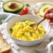 Healthy egg breakfast plate with scrambled eggs, avocado, whole grain toast, and tomatoes