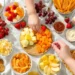 Simple picnic food ideas for kids including sandwiches, fruit, and finger foods on a checkered blanket