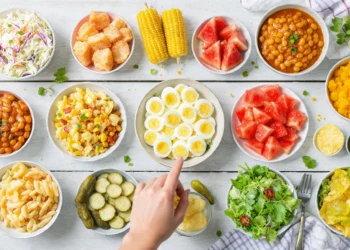 A spread of 15 colorful cookout side dishes including pasta salad, coleslaw, and grilled vegetables on a picnic table