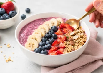 Easy summer smoothie bowl topped with fresh berries, granola, and sliced banana in a white bowl