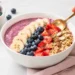 Easy summer smoothie bowl topped with fresh berries, granola, and sliced banana in a white bowl