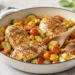 One pan summer chicken dinner with roasted vegetables and herbs in a cast iron skillet