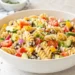 Quick cold pasta salad with rotini, cherry tomatoes, olives, and Italian dressing in a white bowl