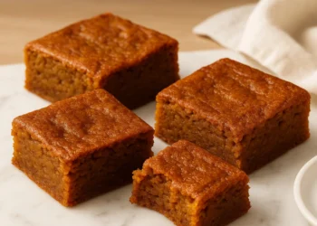 Assortment of autumn desserts including apple cinnamon cake, pumpkin cookies, and caramel treats on a wooden table