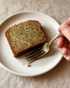 A slice of moist gluten-free zucchini bread with a tender golden crumb on a white plate