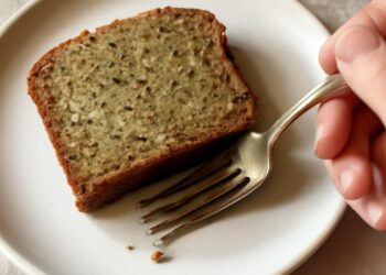 A slice of moist gluten-free zucchini bread with a tender golden crumb on a white plate