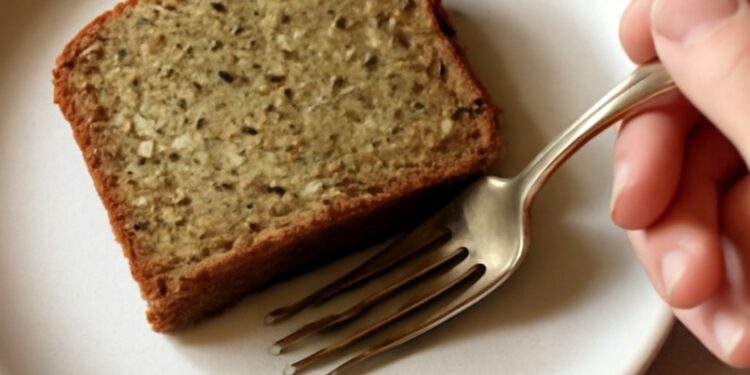 A slice of moist gluten-free zucchini bread with a tender golden crumb on a white plate