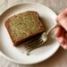 A slice of moist gluten-free zucchini bread with a tender golden crumb on a white plate