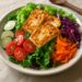 Colorful rainbow salad with warm grilled halloumi cheese, mixed fresh vegetables, and vinaigrette dressing