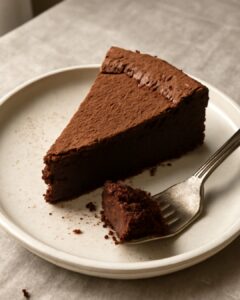 A slice of rich flourless chocolate cake with a fudgy center on a white plate