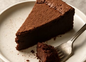 A slice of rich flourless chocolate cake with a fudgy center on a white plate