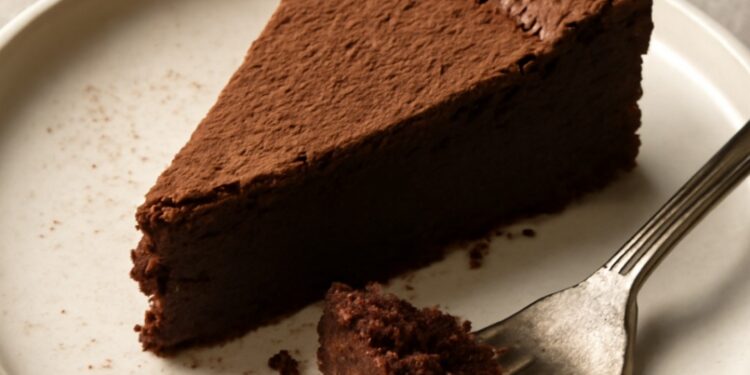 A slice of rich flourless chocolate cake with a fudgy center on a white plate